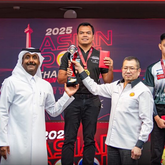 Carlo Biado holding the trophy after winning the 2025 Asian 10-Ball Championship while standing on the podium with officials.